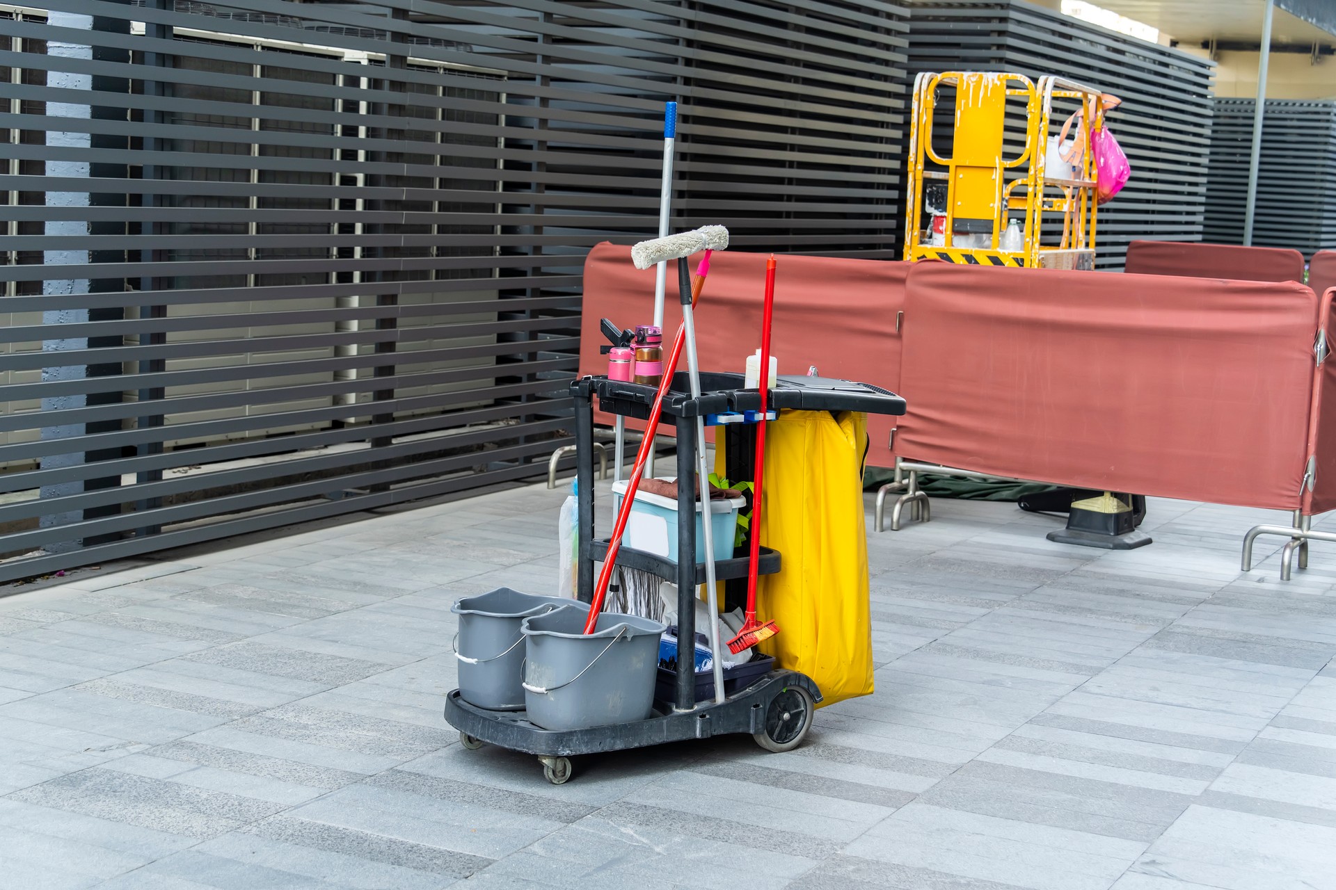 Cleaner cart in a public place with cleaning products: mop, buckets for cleaning the floor, broom scoop, household chemicals, household rags